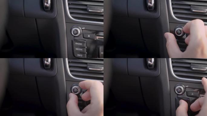 在框架中，一个男人的手和一个汽车音频音量旋钮。驾驶员或乘客调整音乐的音量水平