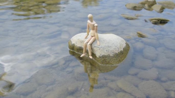 坐在河边的石头上的有关节的小矮人