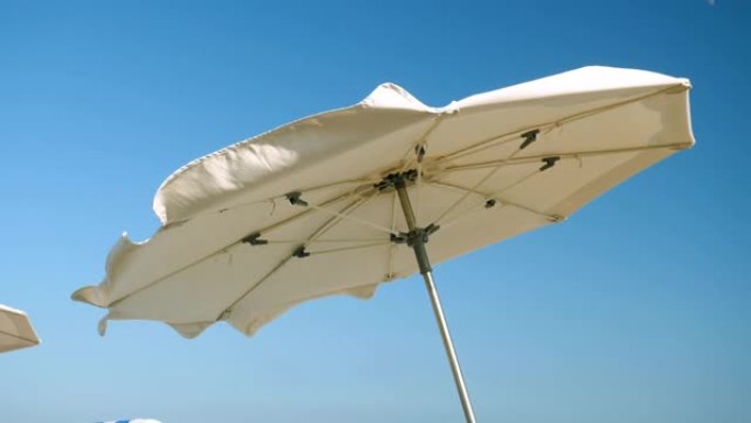 科斯塔德尔马雷斯梅海岸。太阳伞在强风中挥舞的特写镜头。西班牙。慢动作。高清