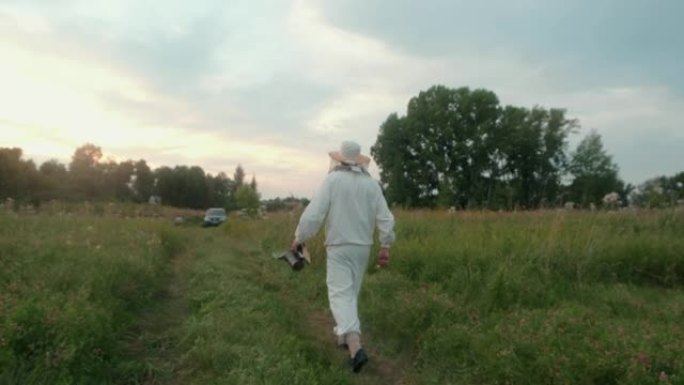 穿着白色防护服的养蜂人沿着乡村散步