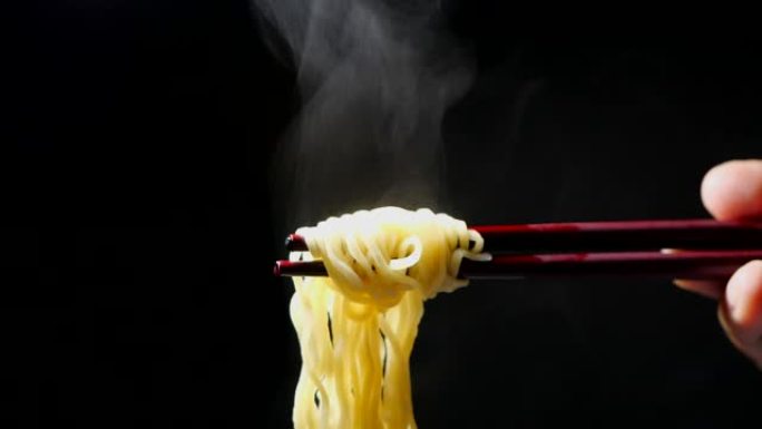 慢动作，亚洲餐特写，垃圾食品和快餐概念的黑色背景上的蒸汽和烟雾筷子