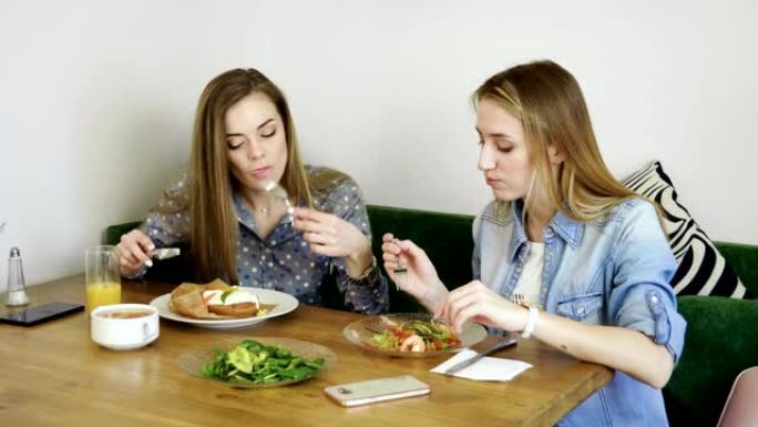 食物和饮料。两个迷人的女孩在餐厅吃饭时聊天。4K