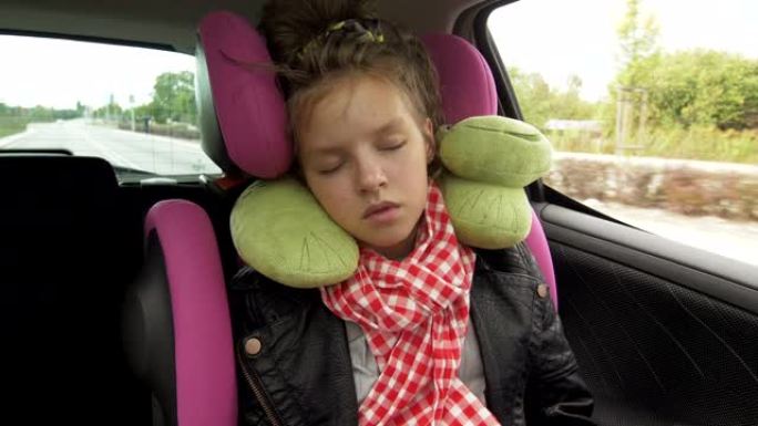 童年公路旅行和人们的概念 -- 十几岁的女孩睡在带旅行枕头的婴儿汽车座椅上