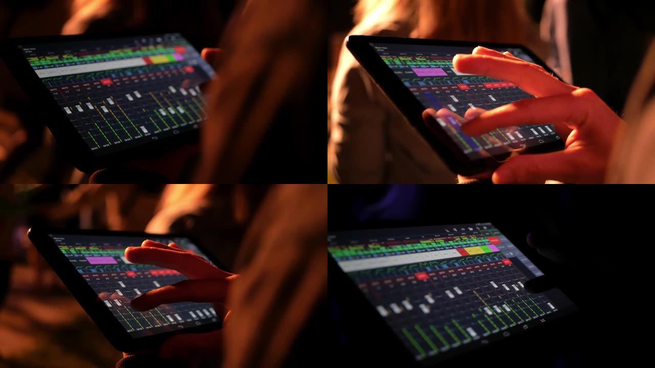 音响工程师使用大型平板电脑上的程序远程调整音乐会上的声音。在音乐组表演期间控制滑块设置。