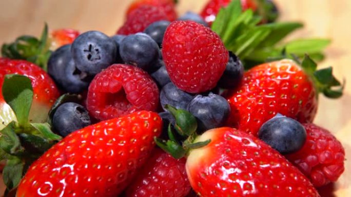 盘上旋转的新鲜森林浆果数量的俯视图。成熟的草莓、黑莓和覆盆子。人体的各种营养特性。健康饮食，浆果混合