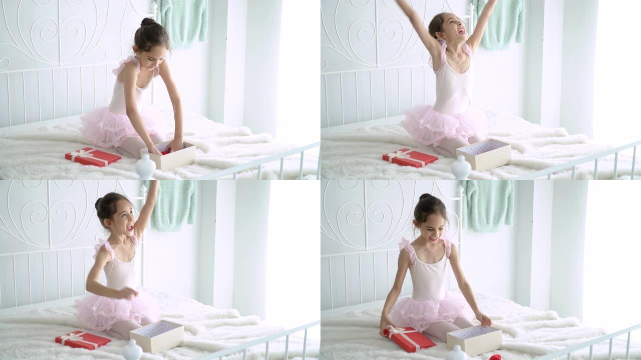 4k中拍摄的快乐美丽的小女孩，穿着粉红色的芭蕾舞短裙和紧身连衣裤，坐在卧室的床上，玩迷你红心。穿着粉