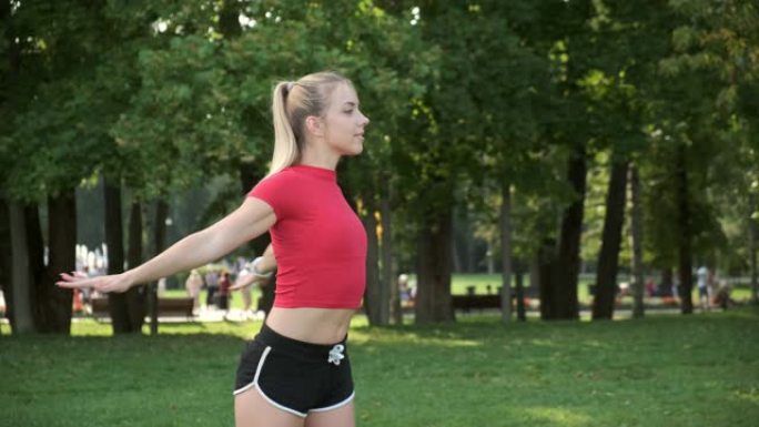 运动体质的年轻漂亮女孩在公园里从事健身。运动员在训练和做瑜伽之前进行热身