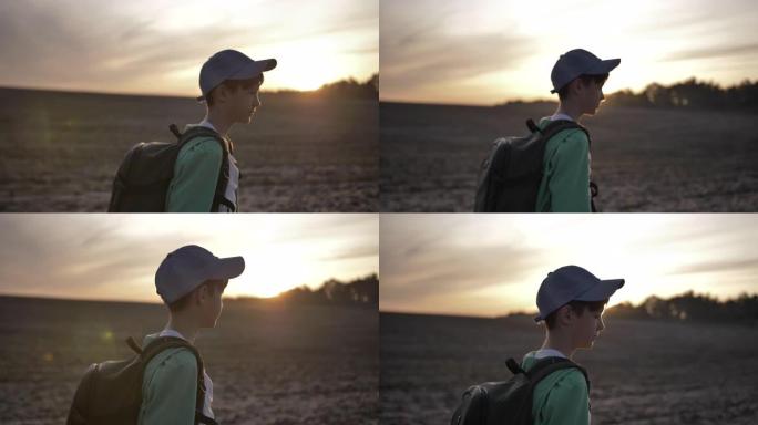 带着背包的旅行男孩在日落时走在户外