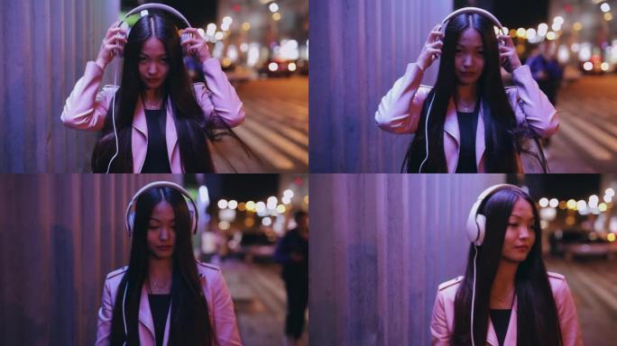 亚洲妇女在夜城穿上耳机行走