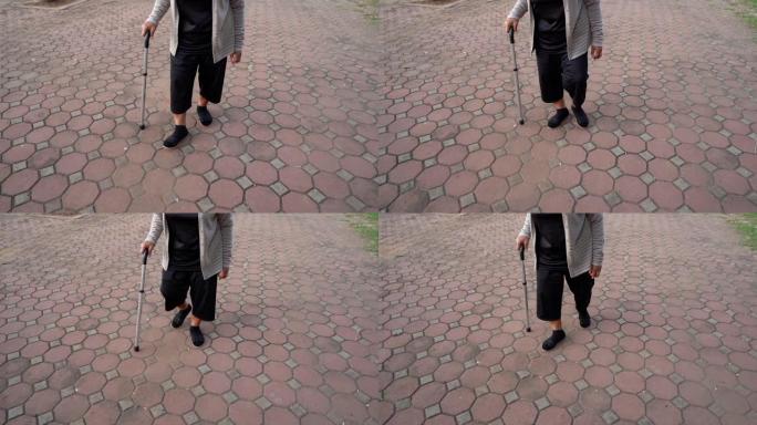 公园里用拐杖走路的高级女性腿的慢速运动