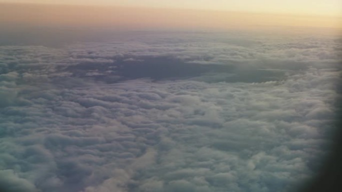 从飞机的窗户看。飞机在地面和云层上飞得很高。从舷窗观看