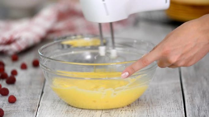 烹饪和家居概念。特写，女人用手动搅拌器打蛋羹。甜奶油的制备。
