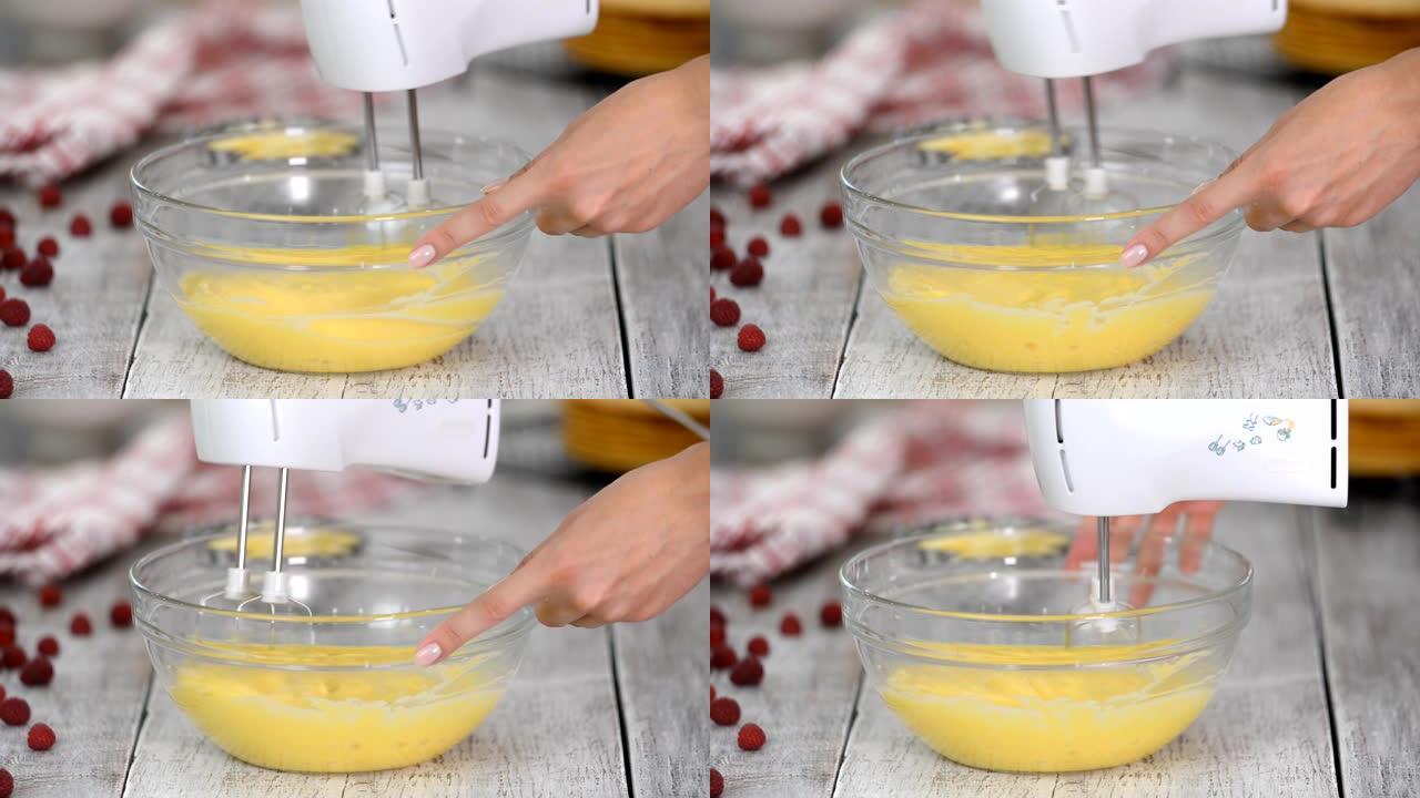 烹饪和家居概念。特写，女人用手动搅拌器打蛋羹。甜奶油的制备。