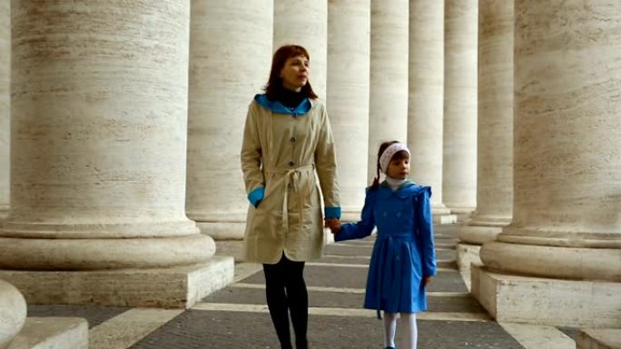 女人和女儿在梵蒂冈圣彼得罗广场的柱子之间行走