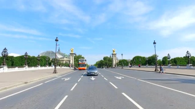 在春季晴天，巴黎亚历山大三世大桥上的汽车和公共汽车朝着小皇宫和大皇宫的方向行驶