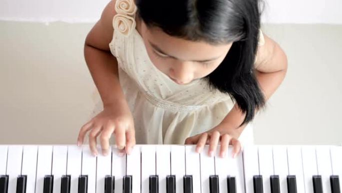 俯视图穿着白色连衣裙的女孩正在弹钢琴。