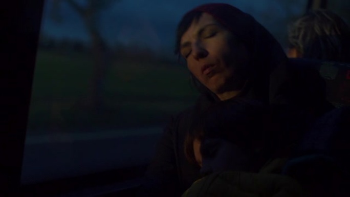 一个女人一大早就睡在公共汽车的椅子上。在黑暗中。