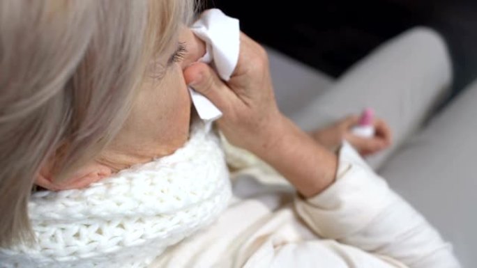 生病的老妇使用鼻喷雾剂在组织中打喷嚏，季节性过敏问题