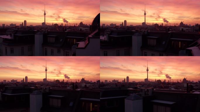 空中: 柏林电视塔亚历克斯/亚历山大广场的美丽景色，日出时在红色的晨光下在屋顶上冒烟 (冬季，大城市