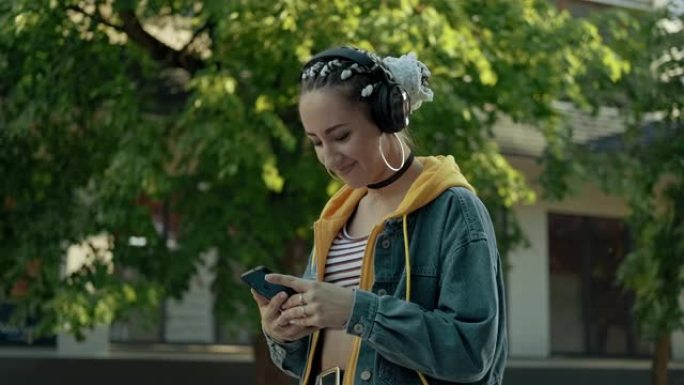 迷人的女人在city walk上使用智能手机在耳机中听音乐