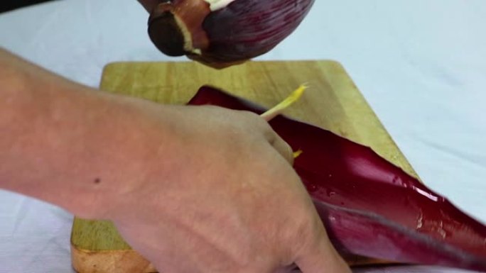 人的手正在剥香蕉花的苞片，准备香蕉芽做饭或沙拉。