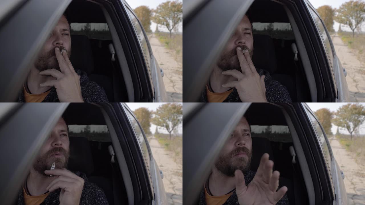一个迷人的大胡子男人在开车时抽烟的肖像。在车里抽烟的家伙。4k. 4k视频。慢动作。23.98 fp