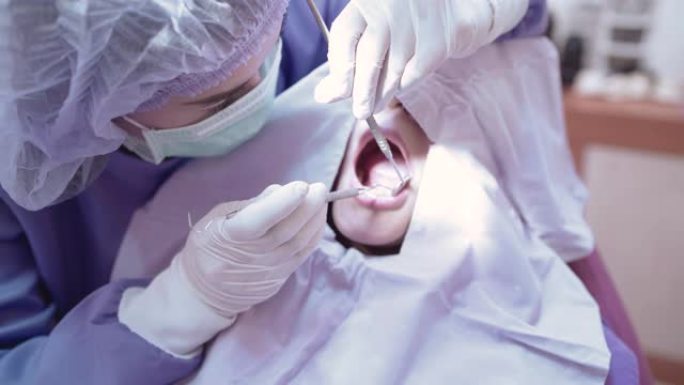 女性牙齿充填检查牙医在诊所通过挖掘机和镜子检查她的病人美丽的微笑