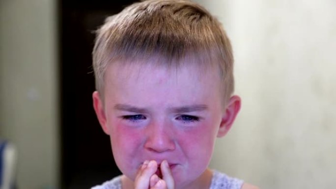 男孩在哭。红脸。孩子用手摩擦眼睛。特写。