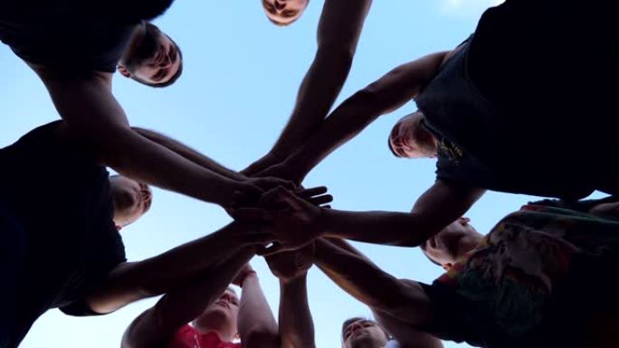 年轻的运动员们团结一致地将他们的双手一一叠在一起。一群最好的朋友把他们的手臂放在一个圆圈的中心，把他