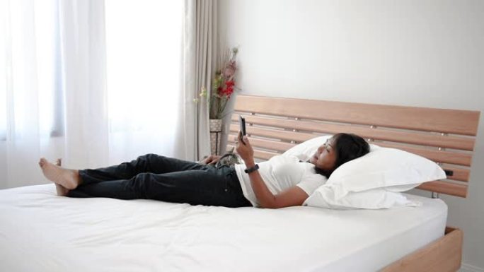 亚洲女性使用智能手机在现代卧室玩虎斑猫。