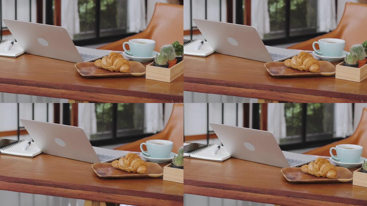 关闭笔记本电脑，咖啡杯在没有人的咖啡店的木桌上