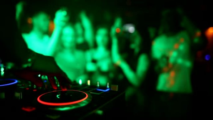 女性DJ手在转盘上混合，年轻人在背景中跳舞。当她打破节奏时，迪斯科俱乐部已经满了