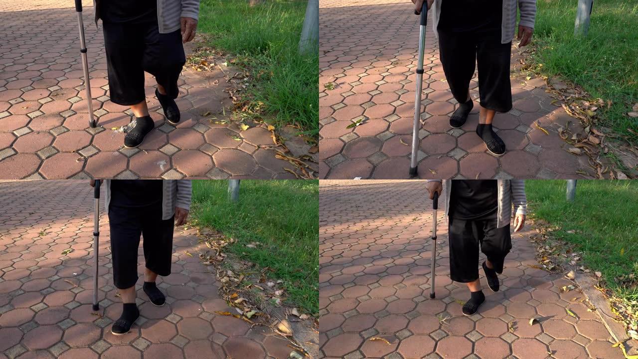 关闭在公园里用拐杖走路的高级女性腿