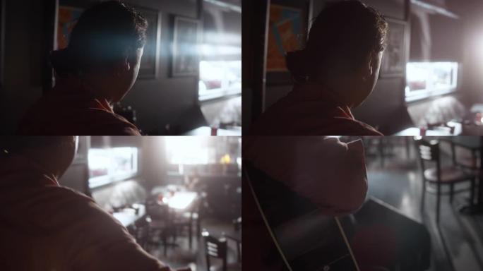 在一个拉丁裔血统的人的肩膀上，他在一个空的酒吧里弹奏木吉他，阳光普照