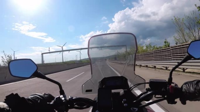 骑摩托车的人骑在奥地利风力涡轮机农场附近的高速公路上。视点