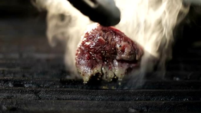 库克用金属钳在电烤架上翻转一块鲜肉。