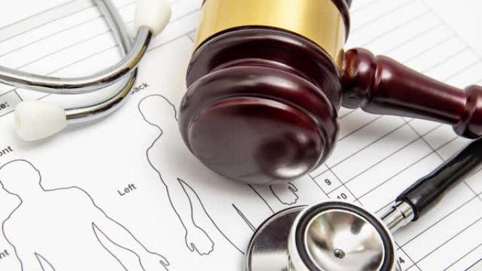 医学图表上的木制法官木槌和听诊器。医疗纠纷概念。