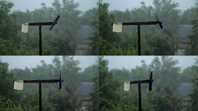 黑色风车在绿色花园的阴雨天气中旋转