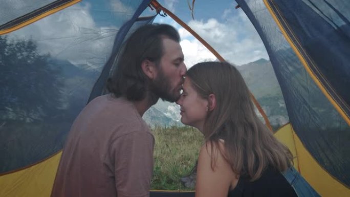 一对男女旅行者在帐篷里接吻。野营旅行的蜜月。浪漫的消遣。雪山历险记