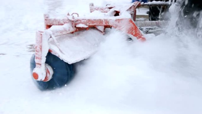 带有扫雪机设备的拖拉机在暴风雪中清除街道上的积雪。