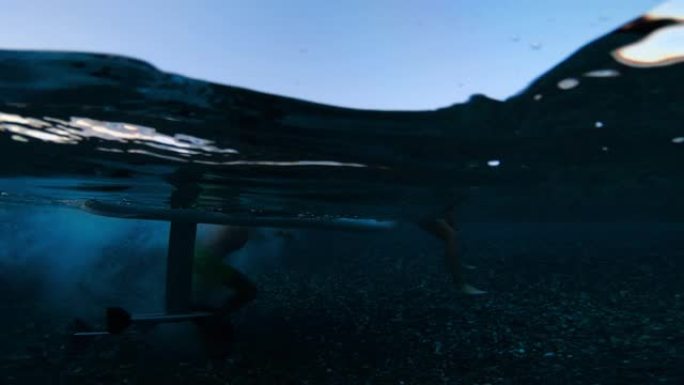 冲浪板上的海上冲浪女性。现代电动水翼冲浪板在go pro相机上的美丽水下视图。冲浪板引擎中的水泡。在