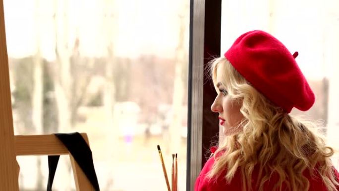 一个穿着红色贝雷帽的女孩的特写镜头，一件红色的连衣裙，在大窗户附近有红色的嘴唇。