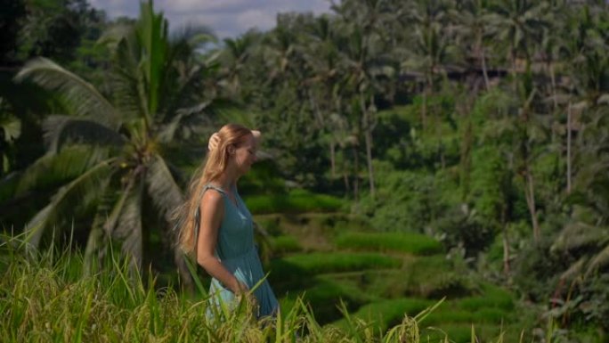 一位穿着蓝色连衣裙的美丽年轻女子的慢动作镜头参观了巴厘岛乌布村著名的Tegalalang水稻梯田