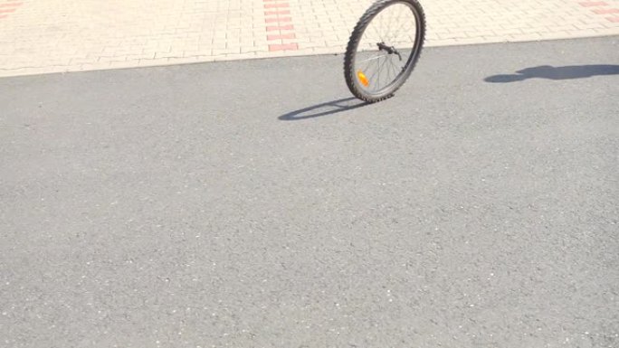 一个坏掉的自行车车轮滚动，一个男孩追赶它