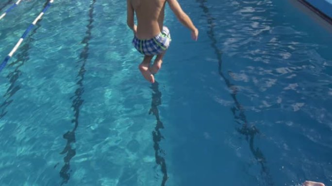 男孩从跳板和跳水在游泳池-慢动作