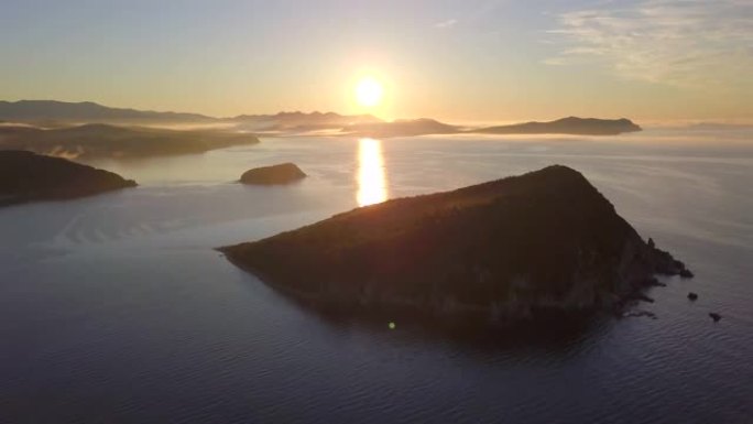 从上面射击。黎明时飞越滨海边疆区拉佐夫斯基保护区受保护的彼得罗夫岛。太阳在海岛的背景下从地平线上升起