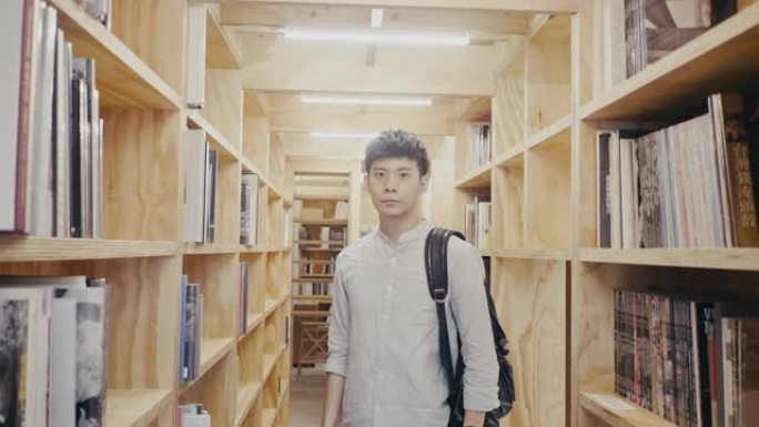 一个年轻的亚洲男学生站在图书馆的肖像 (慢动作)