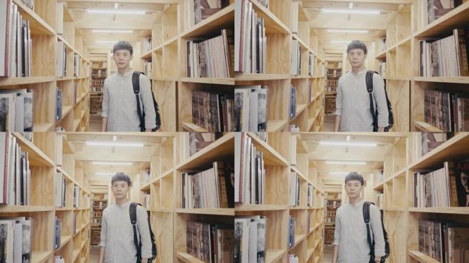 一个年轻的亚洲男学生站在图书馆的肖像 (慢动作)
