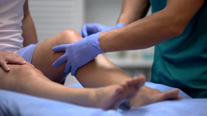 医生戴着手套检查女性患者腿部创伤的膝盖疼痛，医疗保健