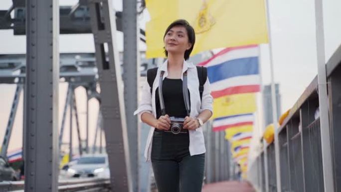 慢镜头:一名亚洲女子在桥上拍照